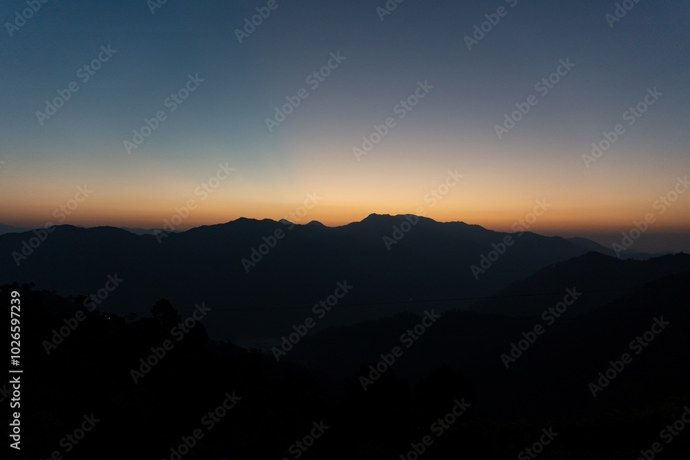 Beautiful dawn view just before sunrise. Horizon and sky looks as orange hues paint the sky.Layered mountains and morning mist create a serene and peaceful sunrise moment in a village of Uttarakhand. Beautiful dawn view just before sunrise. Horizon and sky looks as orange hues paint the sky.Layered mountains and morning mist create a serene and peaceful sunrise moment in a village of Uttarakhand.