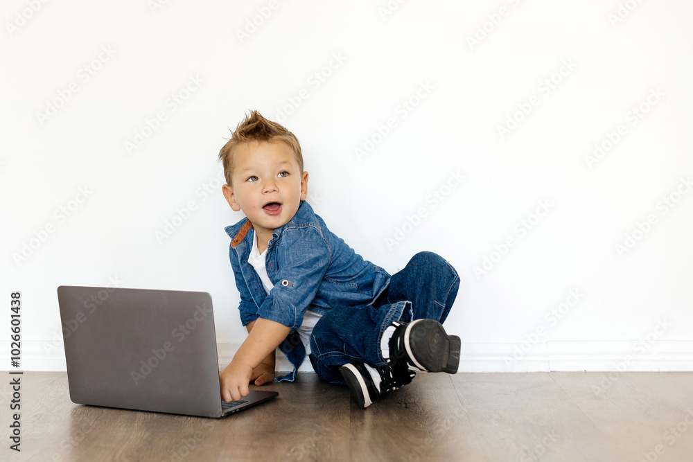 Online Education. A curious child sits on the floor, interacting with a laptop in a bright, clutter-free environment. The playful expression highlights their interest in technology.