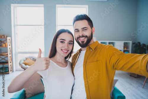 Photo of two young partners selfie thumb up free time modern interior apartment indoors