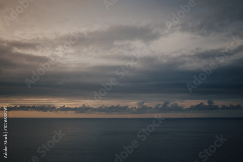 Fototapeta Naklejka Na Ścianę i Meble -  Raining sunset sky over the Atlantic Ocean, Tenerife. Minimalism. Misty dusk in the sea. Dramatic view. Tranquil empty landscape with soft golden gray sky. Natural gloomy weather.