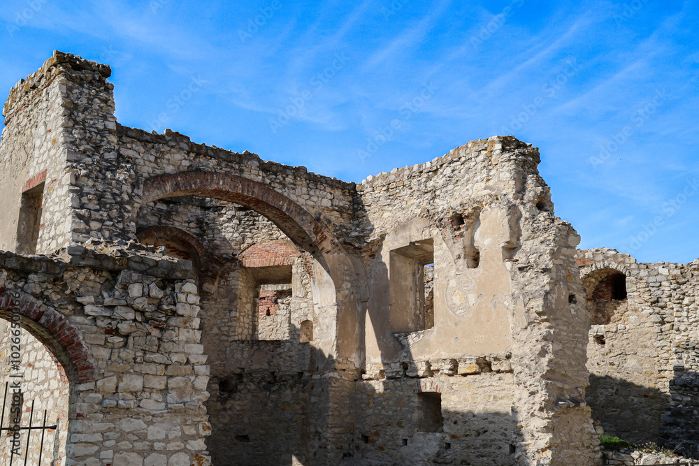 Ruins of Janowiec Castle with arched windows and striped facade against blue sky, historical landmark Ruins of Janowiec Castle with arched windows and striped facade against blue sky, historical landmark