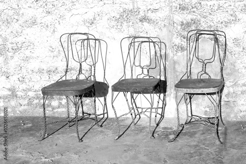 three old rusty metal chairs standing in front of an old wall in India as symbol for time anh history photo