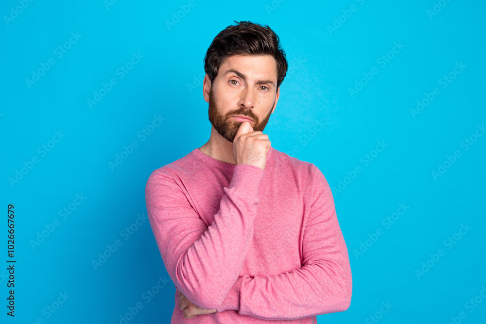 Thoughtful man in pink sweater ponders over blue background portraying contemplation and decision-making concepts Thoughtful man in pink sweater ponders over blue background portraying contemplation and decision-making concepts