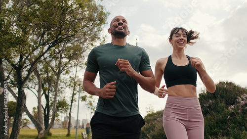 Young joyful active couple jogging together in the park on summer day, bottom-up view