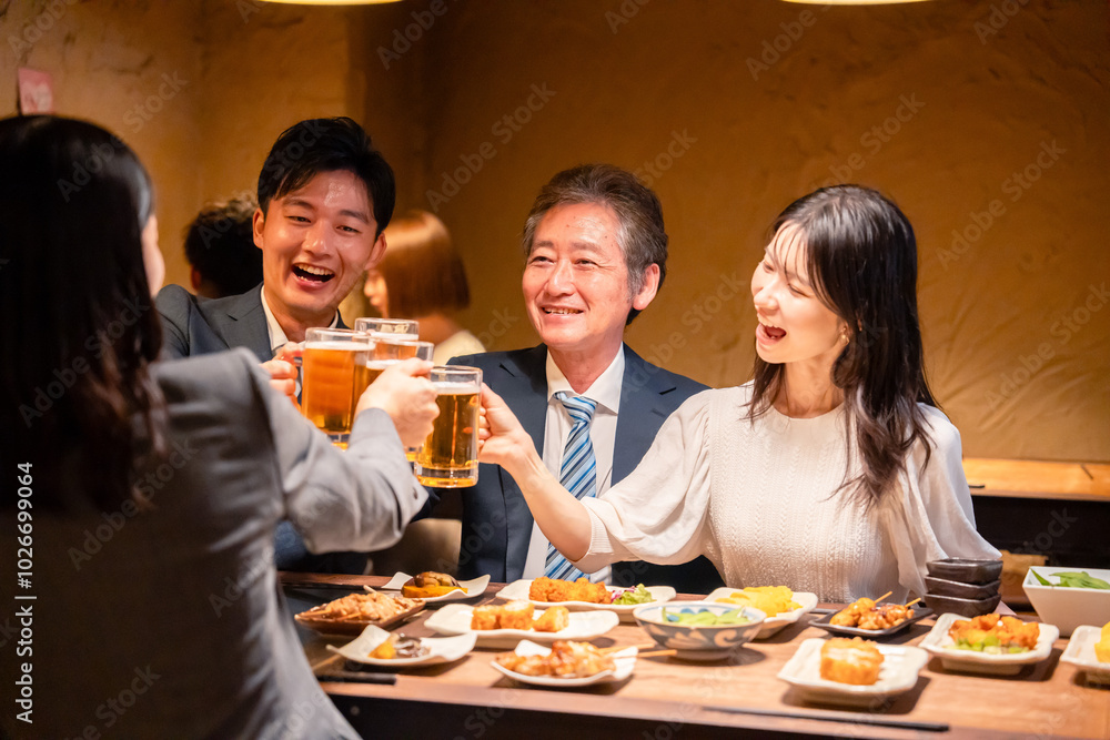 居酒屋で乾杯をする男女のビジネスパーソン 居酒屋で乾杯をする男女のビジネスパーソン