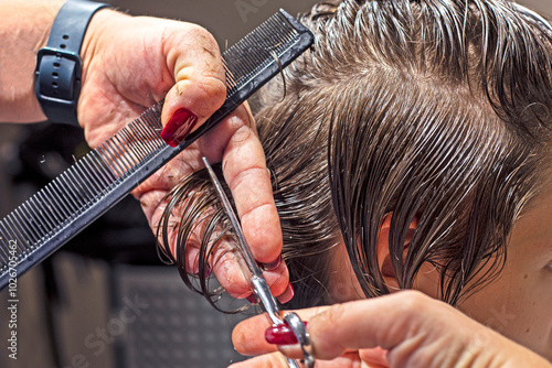 barber cuts a teenager's grown-out hair in a beauty salon. Personal style