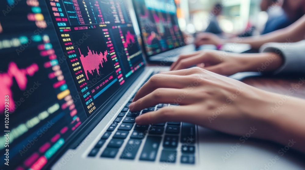 Hands typing on a laptop displaying a stock trading platform, with various charts and market trends visible on the screen. Hands typing on a laptop displaying a stock trading platform, with various charts and market trends visible on the screen.