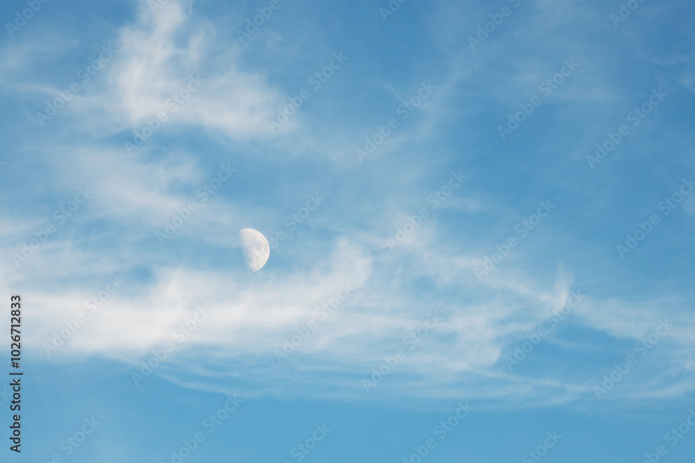 A first quarter moon apparently floats with the clouds in this daylight image A first quarter moon apparently floats with the clouds in this daylight image
