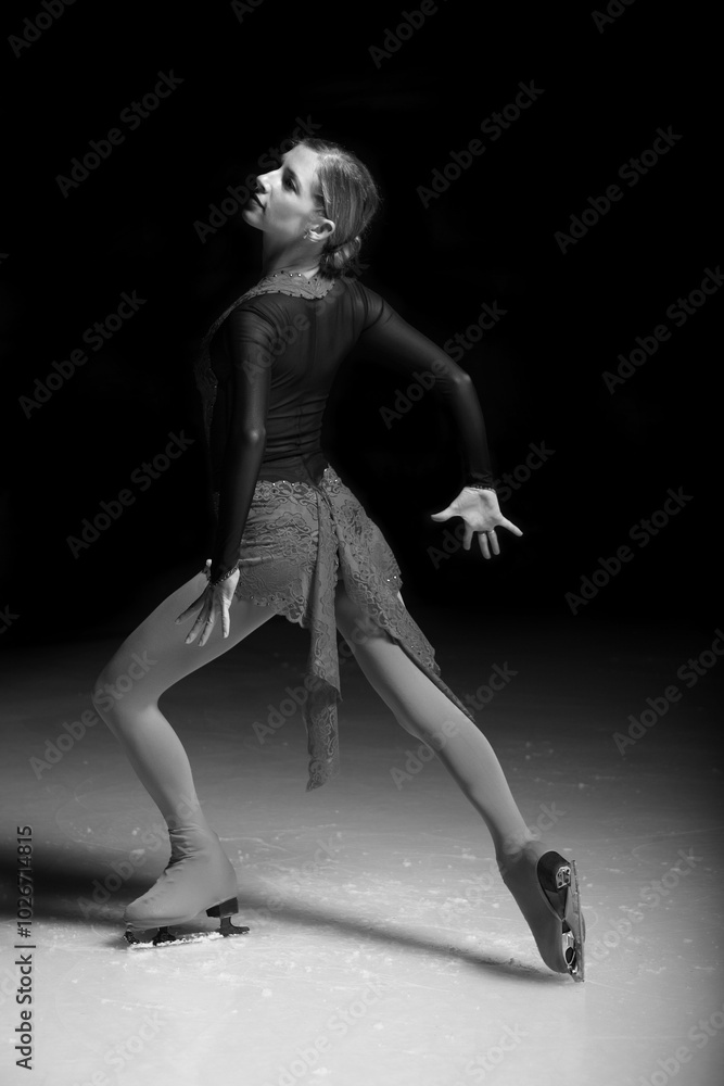 woman figure skater posing on dark background woman figure skater posing on dark background