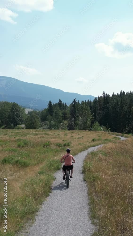 Man on an ebike enjoys a sunny day riding along a winding trail surrounded by nature. Crowsnest Pass, Alberta Man on an ebike enjoys a sunny day riding along a winding trail surrounded by nature. Crowsnest Pass, Alberta