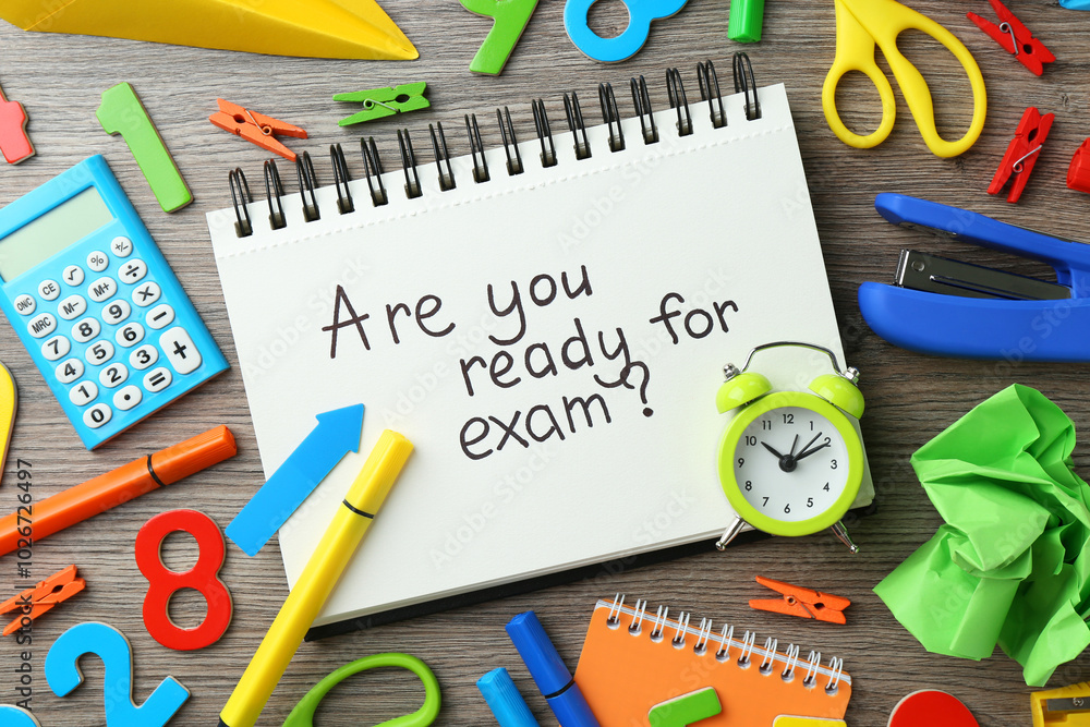 Notepad with question Are You Ready For Exam and stationery on wooden desk, flat lay Notepad with question Are You Ready For Exam and stationery on wooden desk, flat lay