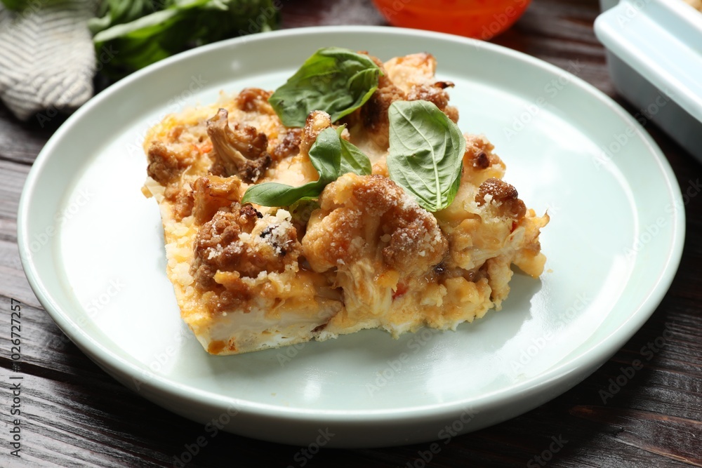 Tasty baked cauliflower and basil on wooden table, closeup Tasty baked cauliflower and basil on wooden table, closeup
