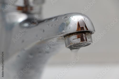 Close up the faucet. Drops of water on the metal tap. Slightly rusted faucet. Flow of water drop. Water shortage concept. Dripping tap. photo