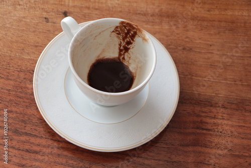 Cup of Turkish Coffee finish drinking, empty dirty cup. A cup of drunk coffee. Concept for completing a meeting or coffee break. Finished cup on the wooden table. Coffee grounds. photo