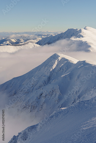 Cloud covered valley and snowy mountains from above, sunny, clear weather, winter, telephoto