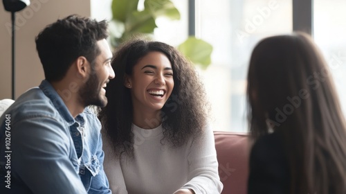 Happy colleagues laughing and collaborating while sitting on a couch, minimal background focusing on their interaction.