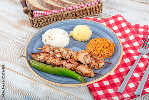 Grilled chicken on bamboo skewers. Chicken garbage skewer grill. Shish tavuk, Chicken shish kebab with french fries on platter. photo