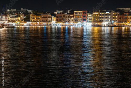 Chania harbor with illuminated houses, people, photographed from the water, night, Greece, Crete island, normal angle lens