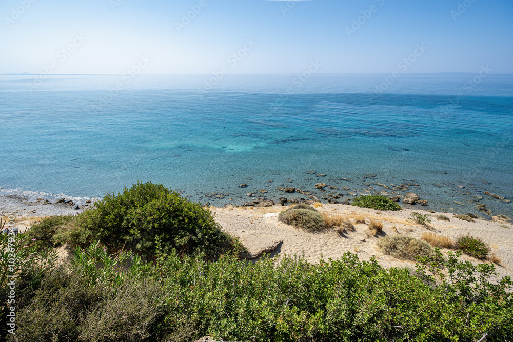 Sandy beach with small rocks, calm sea, clear blue sky, sunny, wide angle lens Sandy beach with small rocks, calm sea, clear blue sky, sunny, wide angle lens