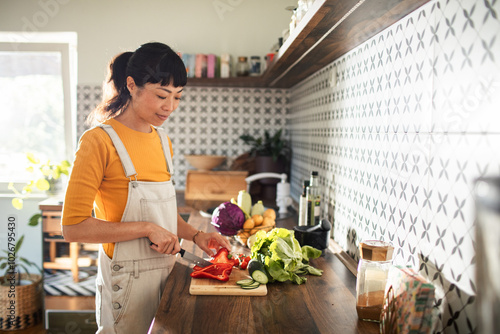 Fototapeta Asian woman chopping vegetables in kitchen for healthy meal prep