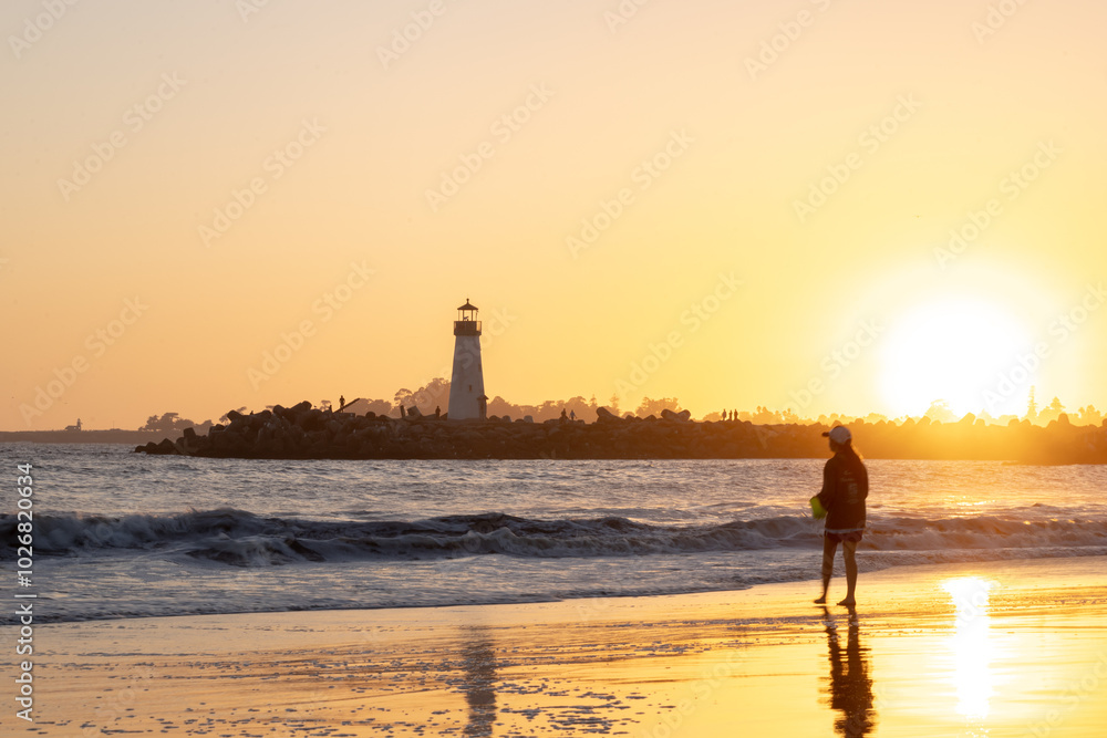 Fototapeta premium The sun was setting, casting a golden glow over the beach. The waves crashed against the shore, their rhythmic sound a soothing balm to the soul.