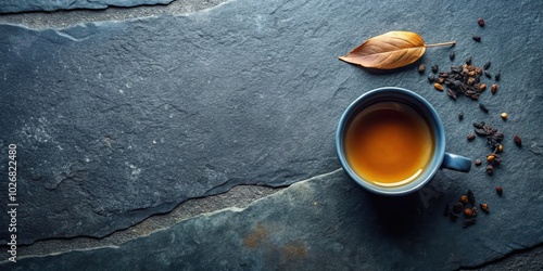 Fototapeta Naklejka Na Ścianę i Meble -  A cup of tea on a slate background with scattered spices and a leaf, hinting at a warm and comforting drink enjoyed in a quiet moment