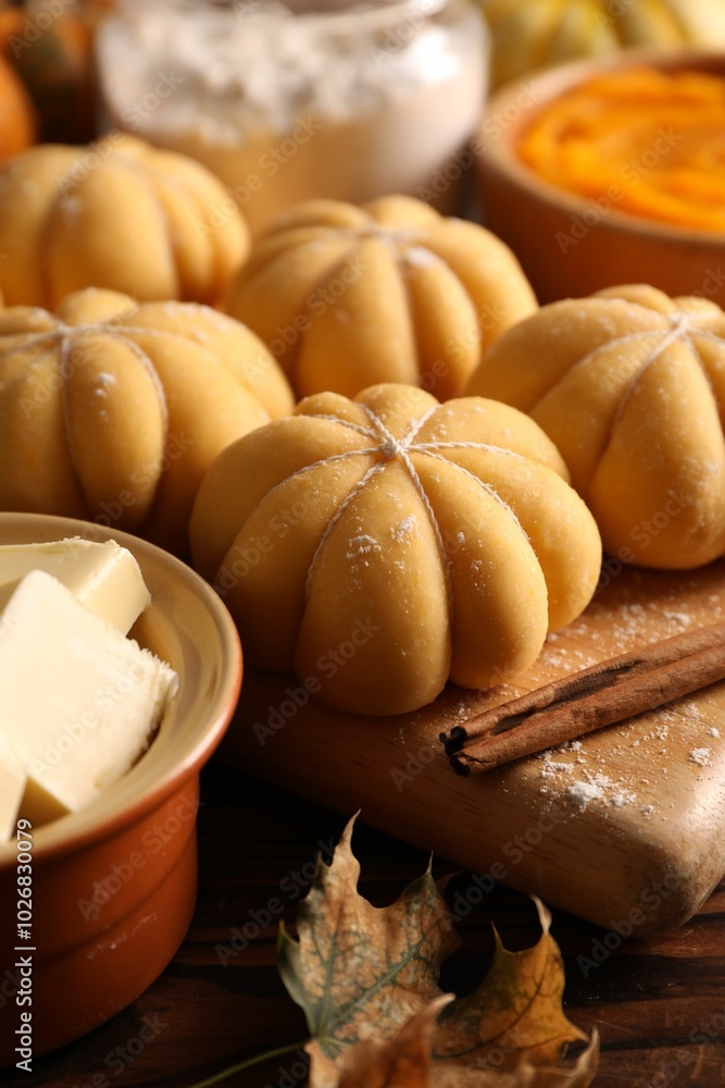 Raw pumpkin shaped buns and ingredients on wooden table, closeup Raw pumpkin shaped buns and ingredients on wooden table, closeup