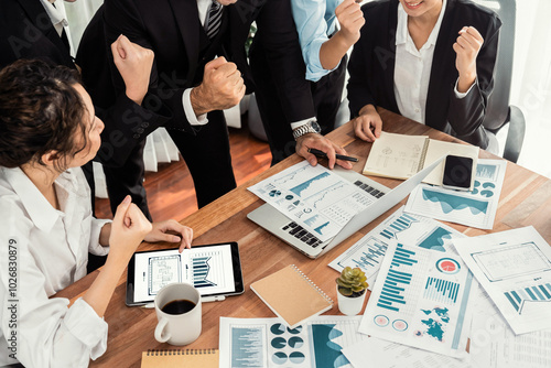 Group of happy businesspeople in celebratory gesture and successful efficient teamwork. Diverse race office worker celebrate after made progress on marketing planning in corporate office. Meticulous