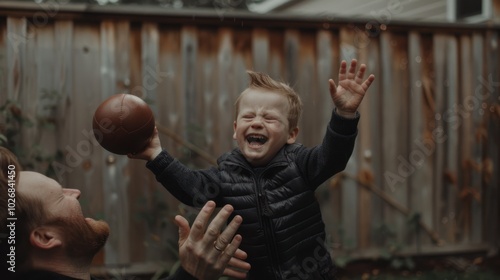 A Boy Laughing While Holding a Football with His Dad photo