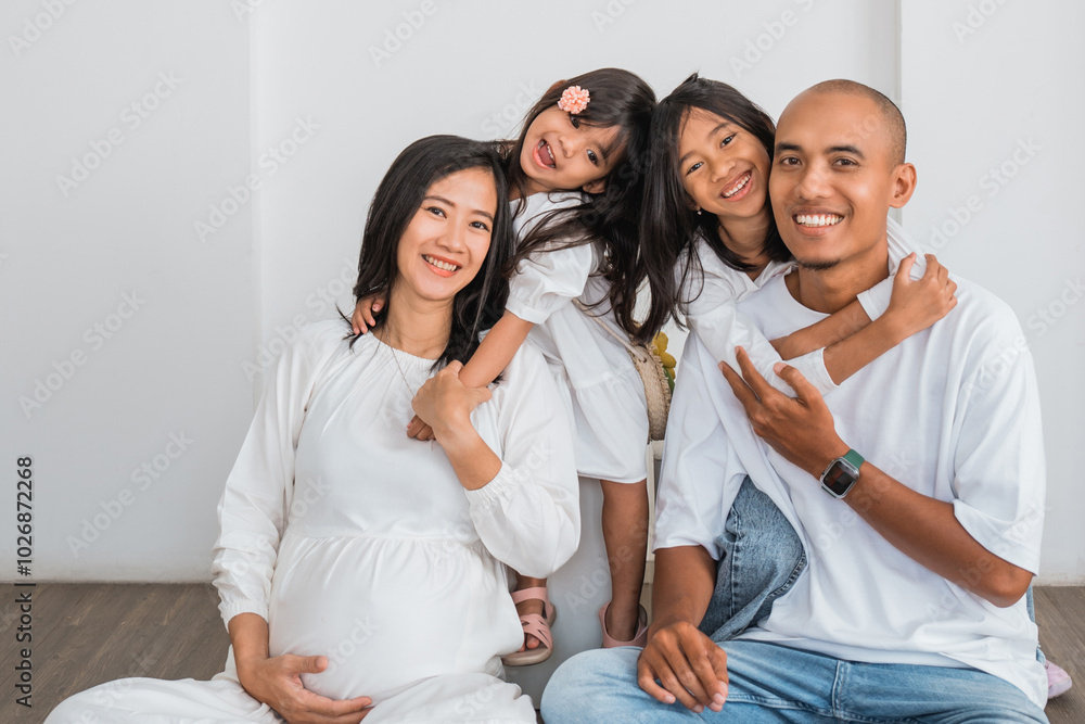 A pregnant woman is comfortably sitting on the floor with her loving family, sharing joyful moments together and enjoying each others company A pregnant woman is comfortably sitting on the floor with her loving family, sharing joyful moments together and enjoying each others company