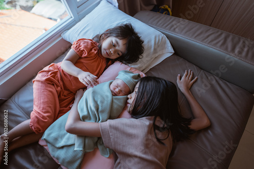 A warm family scene featuring two loving sisters who are caring for a beautiful newborn baby photo