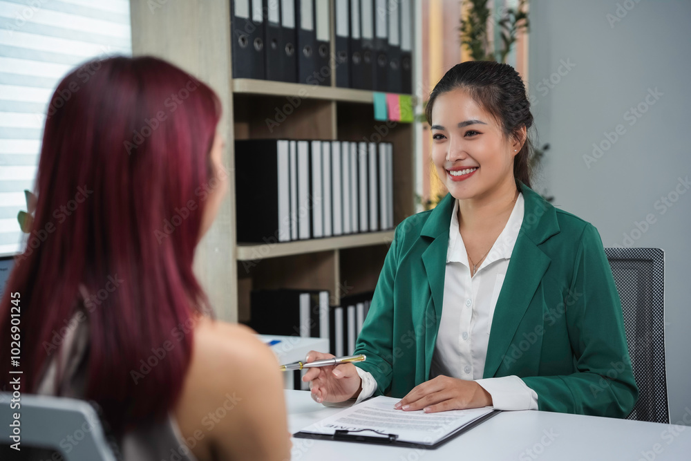 Human resources manager is smiling while holding a job interview with an applicant in the office Human resources manager is smiling while holding a job interview with an applicant in the office