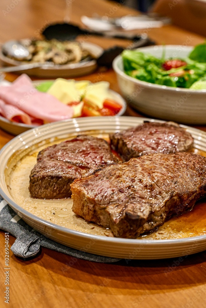 Steak Dinner with Side Dishes. A warm and appetizing spread featuring grilled steaks, seared to perfection, presented on a ceramic plate. Steak Dinner with Side Dishes. A warm and appetizing spread featuring grilled steaks, seared to perfection, presented on a ceramic plate.