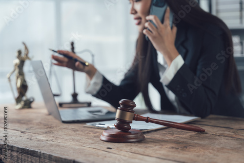 Focused and Determined: A female lawyer works diligently in her office, balancing a phone call, a laptop and a gavel.  She is dedicated to her clients and committed to achieving justice. photo