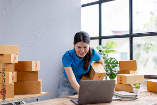 Asian young female sme business owner with product package box at warehouse, merchant seller checking customer address order confirming parcel delivery. 