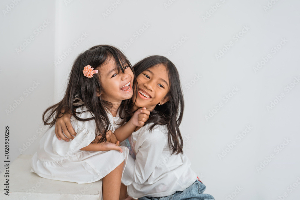 Two little girls are joyfully embracing each other while smiling brightly, showcasing their happiness and friendship in that moment Two little girls are joyfully embracing each other while smiling brightly, showcasing their happiness and friendship in that moment
