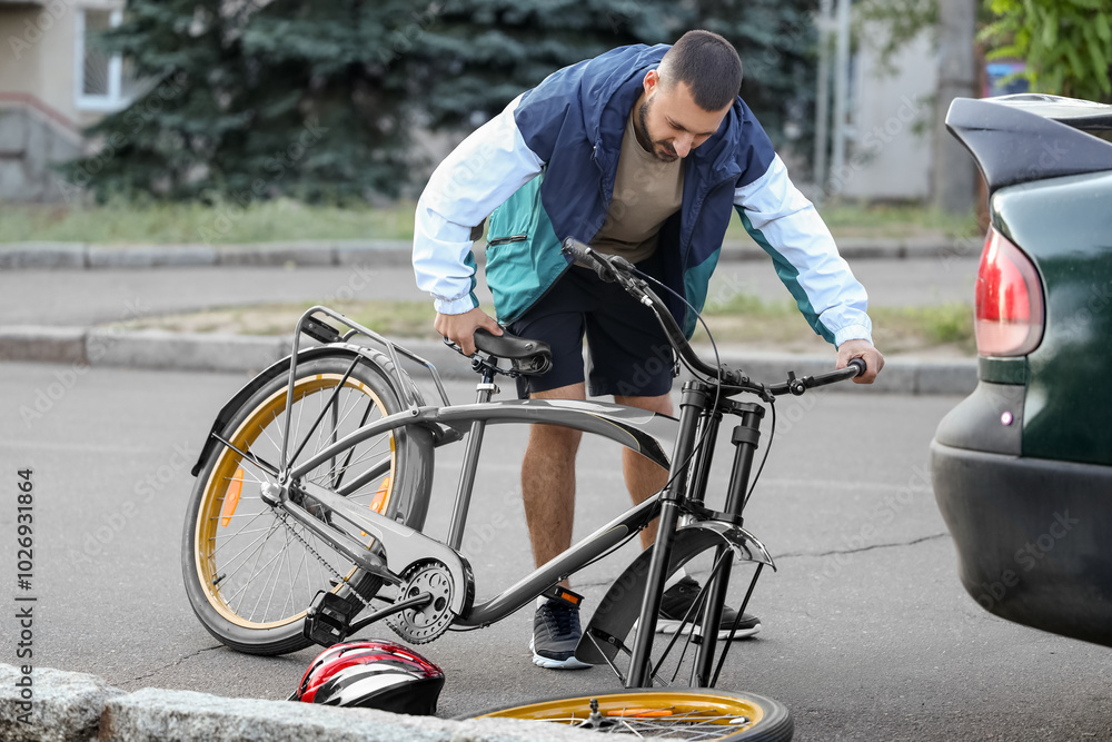 Obraz premium Young male cyclist crashed into car outdoors