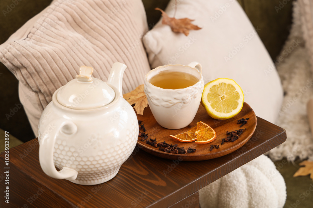 Teapot, cup of green tea, lemon and dried cloves on table in room. Closeup Teapot, cup of green tea, lemon and dried cloves on table in room. Closeup