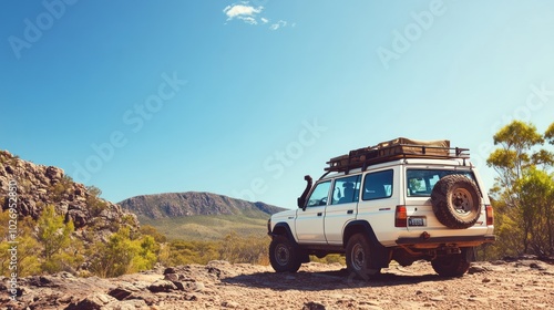 A white off-road vehicle parked on rocky terrain with a scenic mountain backdrop.