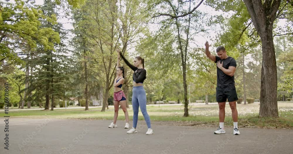 Three friends are warming up for their daily fitness routine together in a green park Three friends are warming up for their daily fitness routine together in a green park