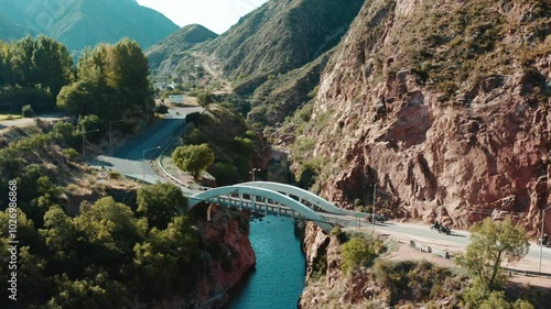 Aerial shot of motorbikers in a road sorrounded of mountains in a canyon.