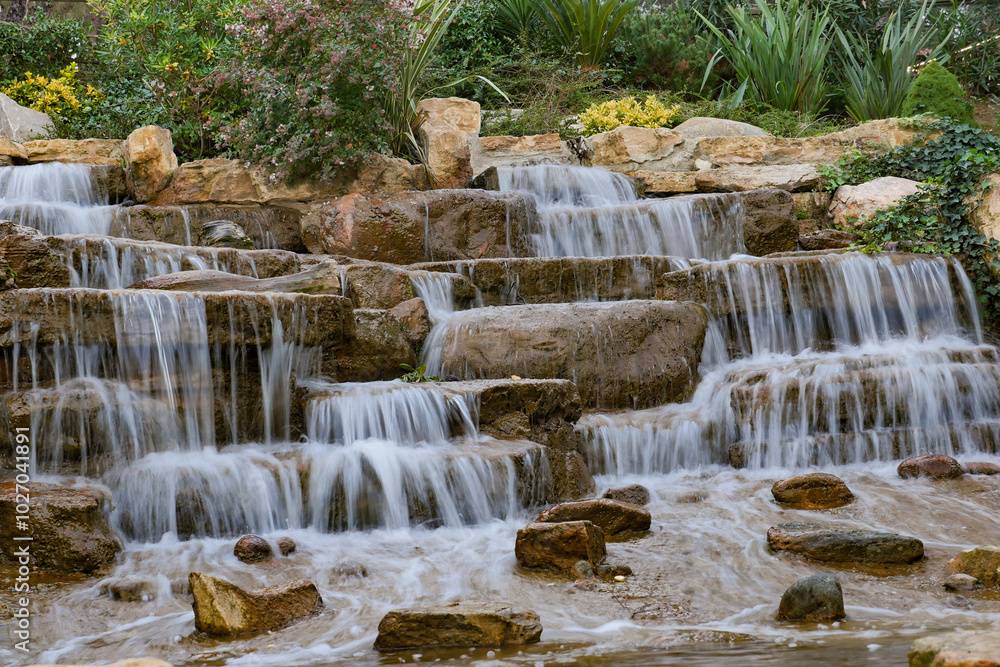 Obraz premium A Beautiful Tranquil Waterfall Cascade Flows Over Natural Stone Steps into a Peaceful Oasis