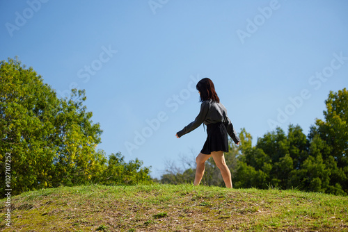 夏の公園で楽しく散歩する一人の女性高校生の姿