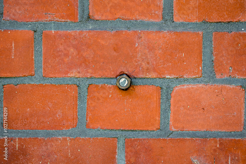 Creative single nano bolt geocache ingeniously embedded in a brick wall, inviting to engage in a thrilling urban treasure hunt, perfect for enhancing passion for exploration or discovery in geocaching