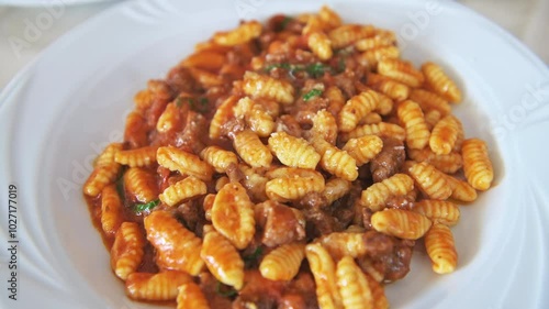 Malloreddos ala ragu della casa traditional sardinian mini dumplings pasta, tomato sauce, beef pork meat cheese on white plate, Sardinia macro closeup