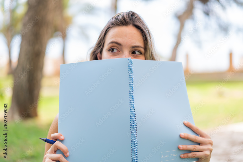 Young pretty woman at outdoors holding a notebook Young pretty woman at outdoors holding a notebook