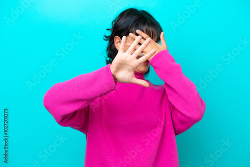 Young Argentinian woman isolated on blue background nervous stretching hands to the front