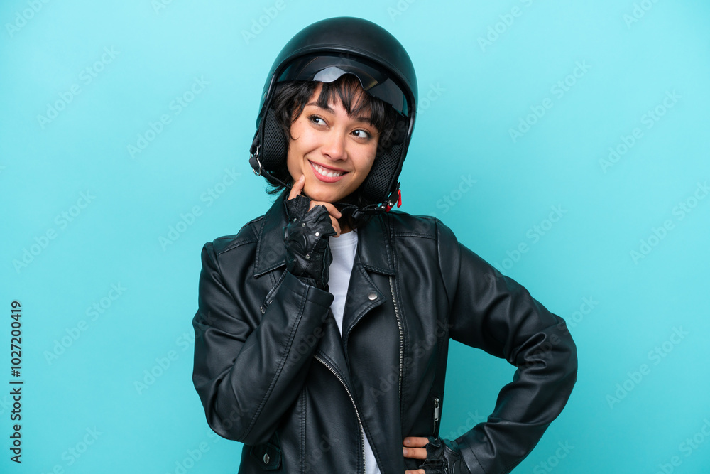 Young Argentinian woman with a motorcycle helmet isolated on blue background thinking an idea while looking up Young Argentinian woman with a motorcycle helmet isolated on blue background thinking an idea while looking up