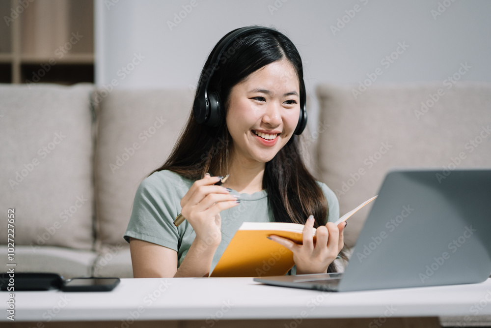 Smiling woman in headphones taking notes, motivated interested student studying online, using tablet, watching webinar training or listening to lecture, remote education concept. Smiling woman in headphones taking notes, motivated interested student studying online, using tablet, watching webinar training or listening to lecture, remote education concept.