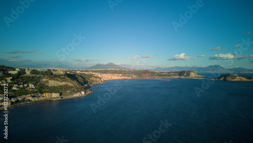 A stunning aerial shot of Pozzuoli, highlighting its scenic coastline and vibrant harbor.The drone captures the ancient Roman ruins, the calm sea, and the natural beauty surrounding the historic city.